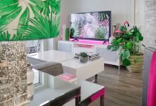 A stylish living room featuring tropical-themed decor, plants, and a modern TV setup.