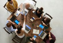Top view of a diverse team collaborating in an office setting with laptops and tablets, promoting cooperation.