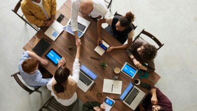 Top view of a diverse team collaborating in an office setting with laptops and tablets, promoting cooperation.