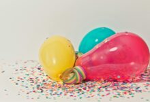 Vibrant colorful balloons surrounded by confetti, perfect for party celebrations.